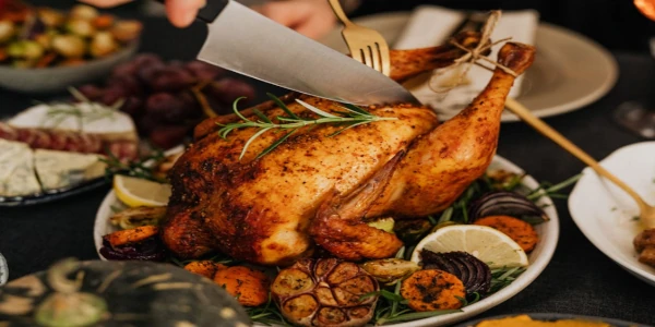 A Thanksgiving Misadventure: An picture of Thanksgving Dinner, The Turkey is getting cut with a knife, On the plate the tureky has carrots, lemons, potatoes, and some rosemary.
